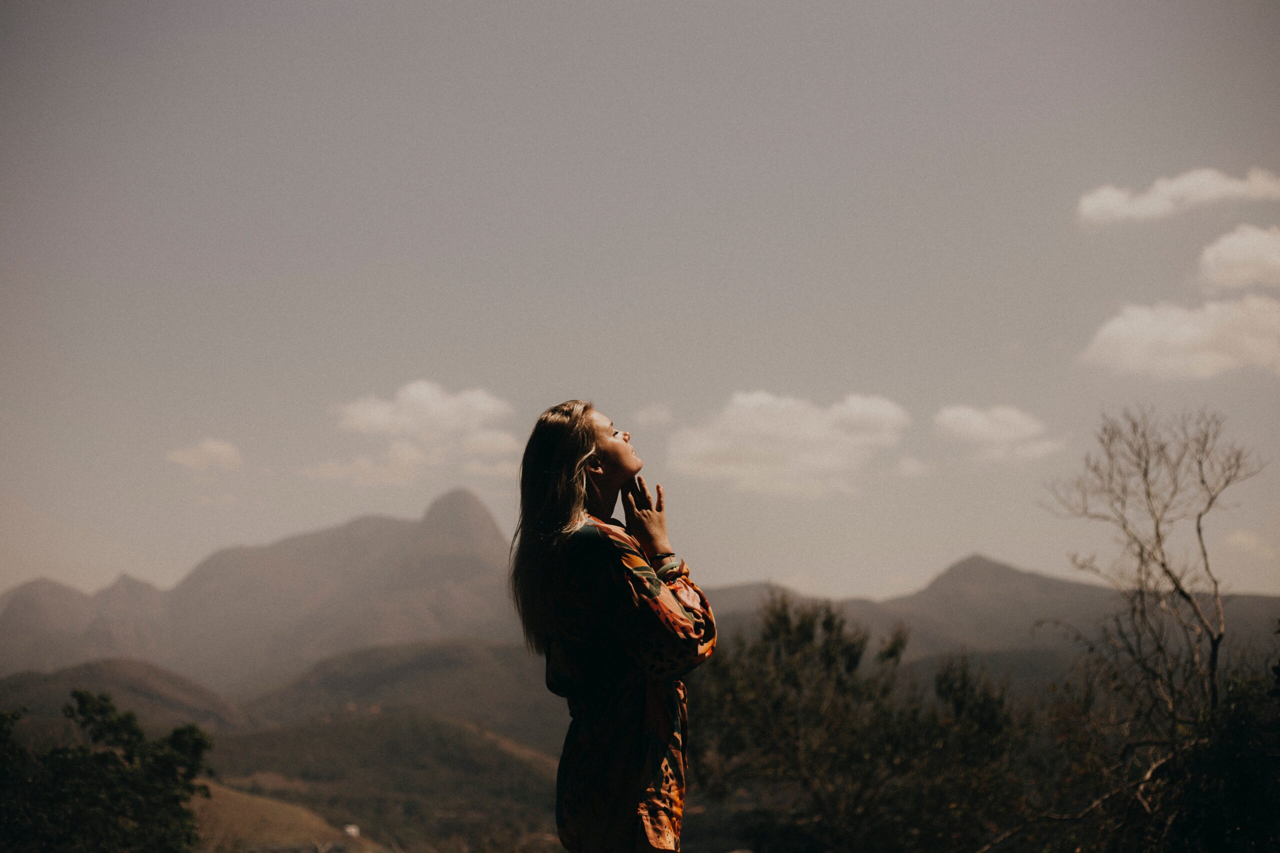 woman in prayer in front of smoky mountains